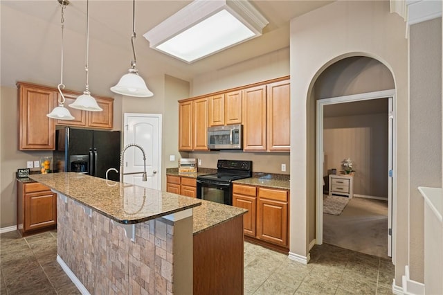 kitchen with decorative light fixtures, light stone counters, a kitchen bar, a center island with sink, and black appliances