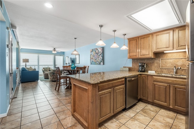 kitchen featuring sink, kitchen peninsula, ceiling fan, stainless steel dishwasher, and pendant lighting