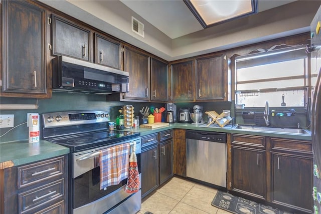 kitchen with light tile patterned floors, stainless steel appliances, dark brown cabinets, and sink