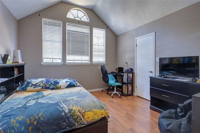 bedroom featuring multiple windows, lofted ceiling, and light wood-type flooring