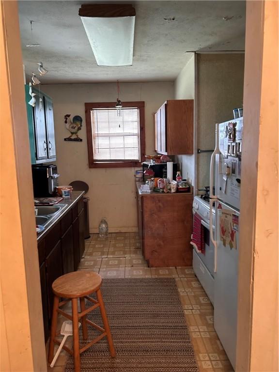 kitchen featuring white appliances, light floors, and a sink