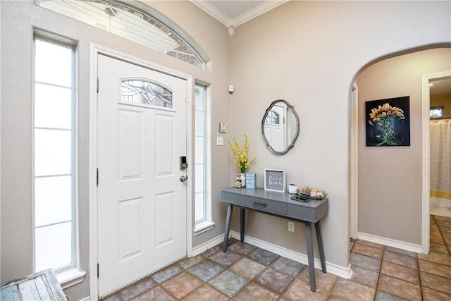 entrance foyer with baseboards, arched walkways, and crown molding