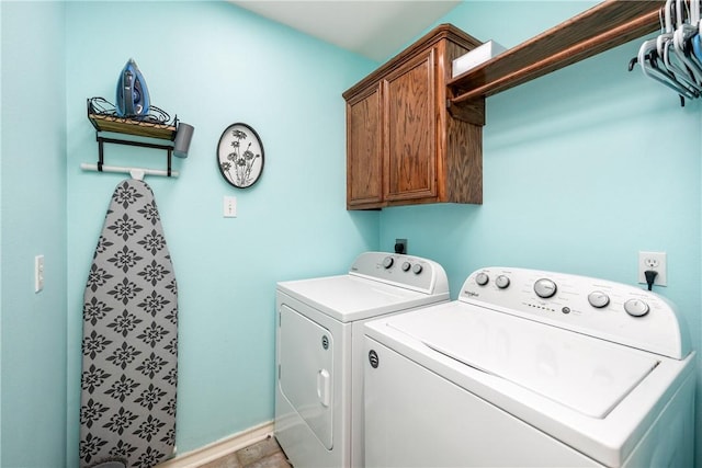 laundry area featuring washing machine and dryer, cabinet space, and baseboards