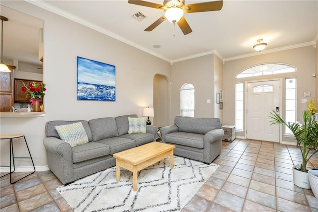 tiled living area with baseboards, visible vents, arched walkways, and crown molding