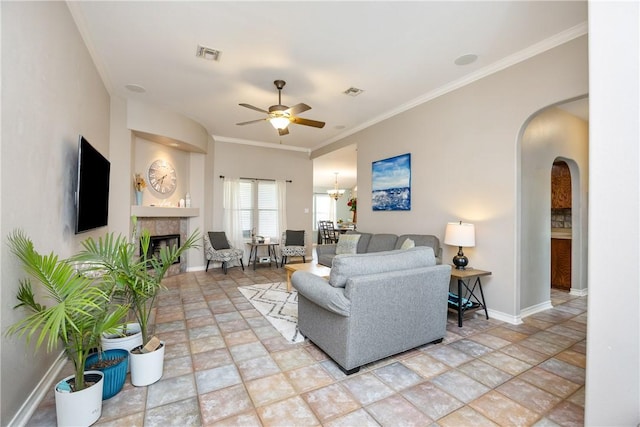 living room featuring arched walkways, visible vents, baseboards, ornamental molding, and a tiled fireplace