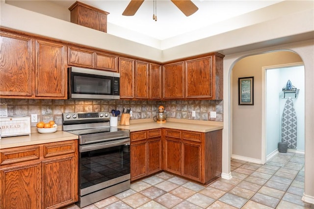 kitchen with stainless steel appliances, arched walkways, light countertops, and tasteful backsplash