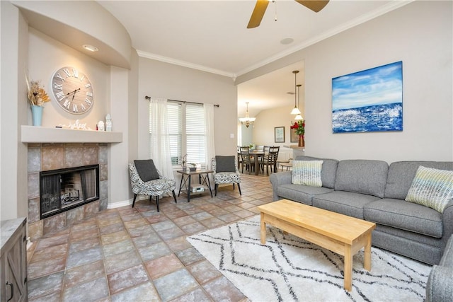 living area with ceiling fan with notable chandelier, ornamental molding, baseboards, and a tile fireplace