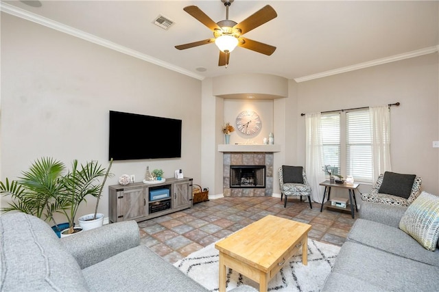 living room featuring baseboards, visible vents, a tiled fireplace, ceiling fan, and ornamental molding