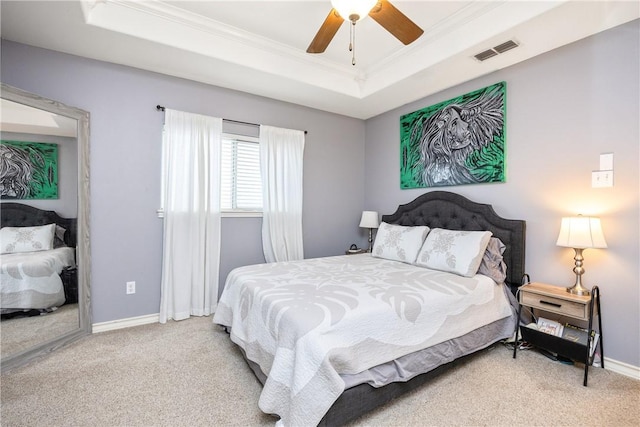 bedroom with light carpet, baseboards, visible vents, ornamental molding, and a tray ceiling