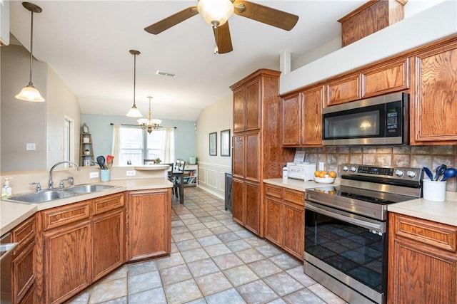 kitchen featuring a sink, light countertops, appliances with stainless steel finishes, hanging light fixtures, and brown cabinets