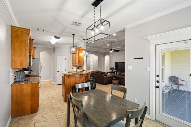3902 Elvis Dr, Corpus Christi, TX 78414 - dining area with arched walkways, crown molding, a ceiling fan, baseboards, and light tile patterned flooring