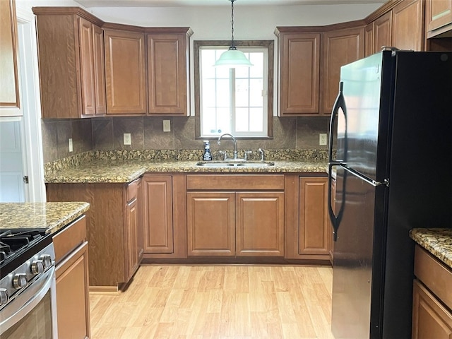 kitchen with decorative backsplash, black fridge, sink, and light wood-type flooring