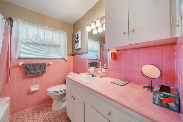 bathroom featuring a wealth of natural light, vanity, toilet, and tile walls