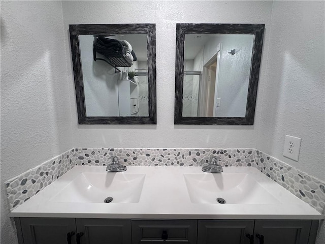 15321 Beaufort Ct, Corpus Christi, TX 78418 - full bathroom with double vanity, a textured wall, and tasteful backsplash