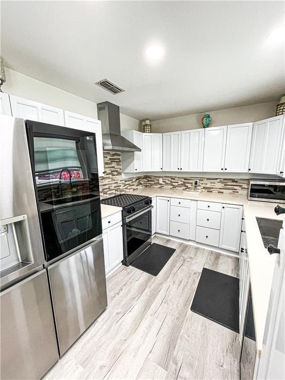15321 Beaufort Ct, Corpus Christi, TX 78418 - kitchen with gas stove, wall chimney range hood, fridge with ice dispenser, light wood-type flooring, and stainless steel microwave