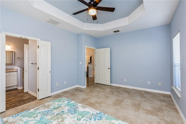 bedroom featuring a raised ceiling, visible vents, connected bathroom, and baseboards