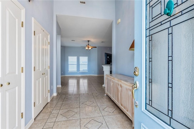 entryway featuring light tile patterned floors, ceiling fan, and baseboards