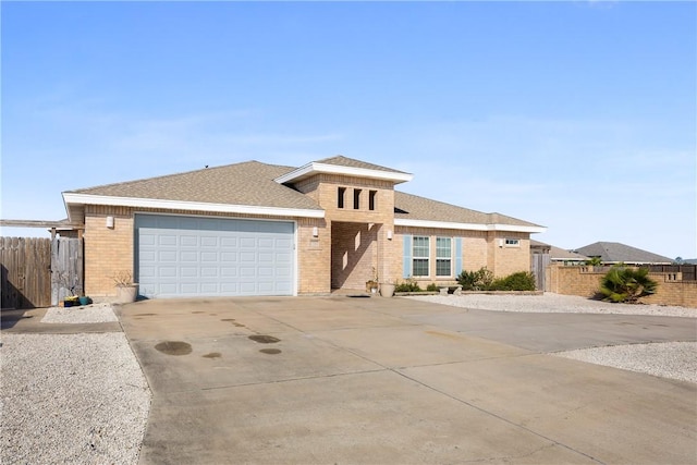 view of front of home with driveway, brick siding, an attached garage, and fence