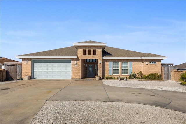 view of front facade featuring a garage, concrete driveway, roof with shingles, fence, and brick siding