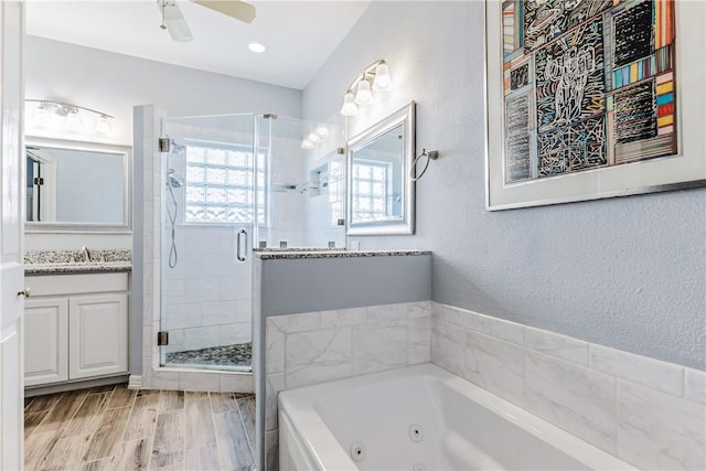 full bathroom with a textured wall, a stall shower, vanity, wood finished floors, and a whirlpool tub