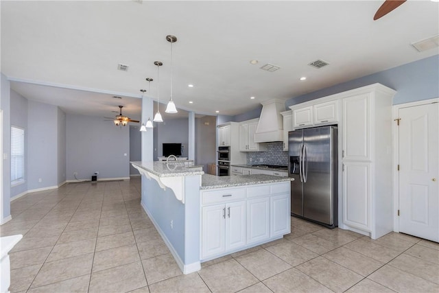 kitchen featuring appliances with stainless steel finishes, white cabinets, a kitchen island with sink, and visible vents