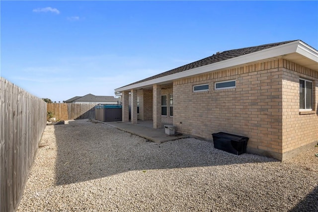 rear view of property with brick siding, a patio area, and a fenced backyard