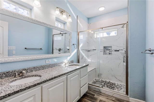 bathroom featuring double vanity, a sink, a marble finish shower, and wood tiled floor