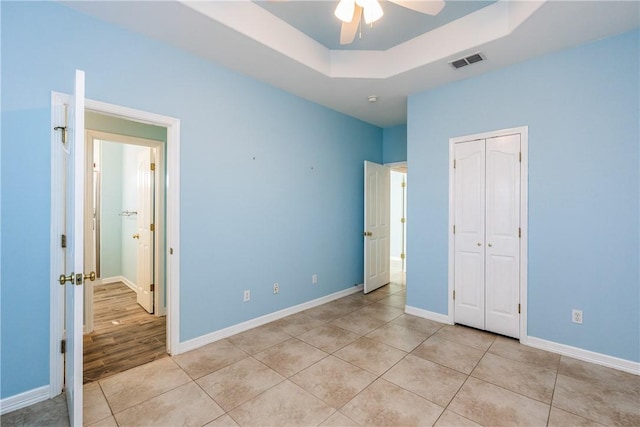 unfurnished bedroom with light tile patterned floors, baseboards, visible vents, and a tray ceiling