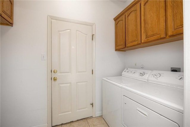 clothes washing area with washing machine and dryer, cabinet space, and light tile patterned floors