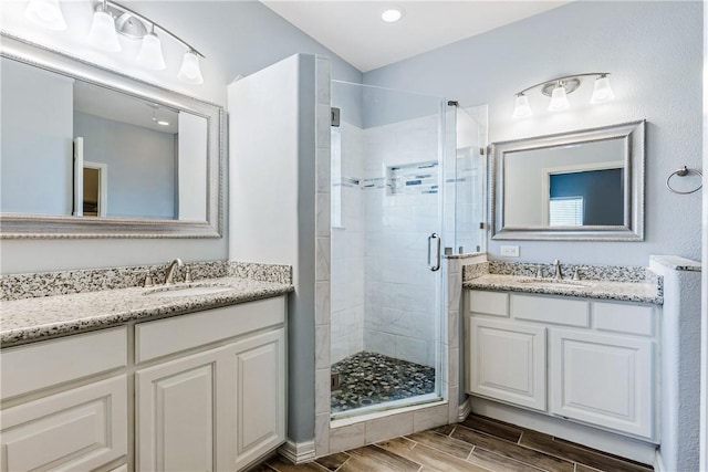 full bath with wood tiled floor, two vanities, a sink, and a shower stall