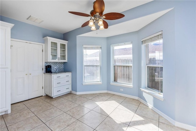 kitchen with glass insert cabinets, white cabinets, visible vents, and light stone countertops