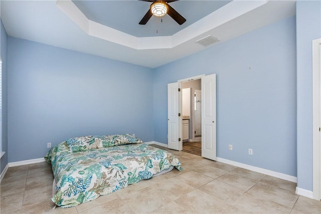 bedroom with a tray ceiling, visible vents, baseboards, and light tile patterned flooring