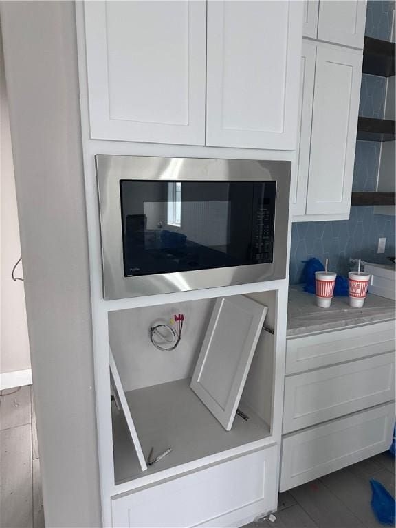 details with built in microwave, tasteful backsplash, and white cabinets