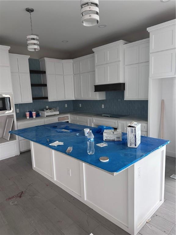 kitchen with white cabinetry, a kitchen island, and backsplash