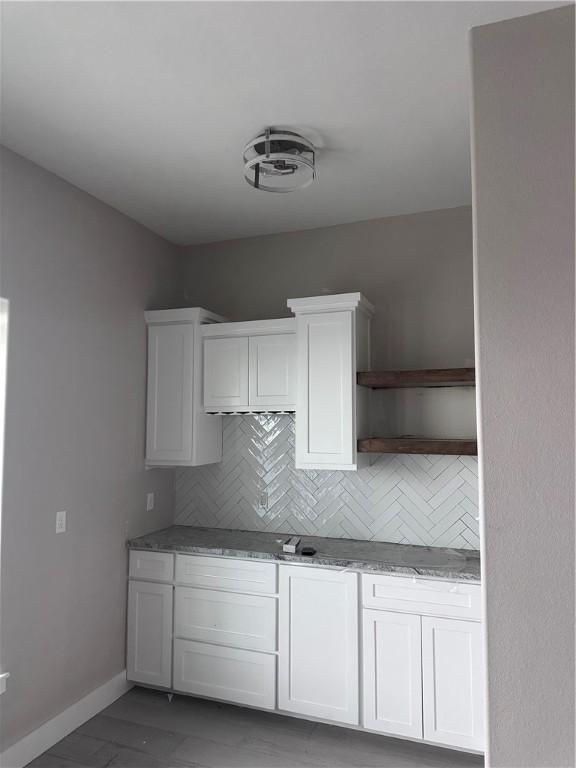 kitchen featuring white cabinetry, light stone countertops, and backsplash