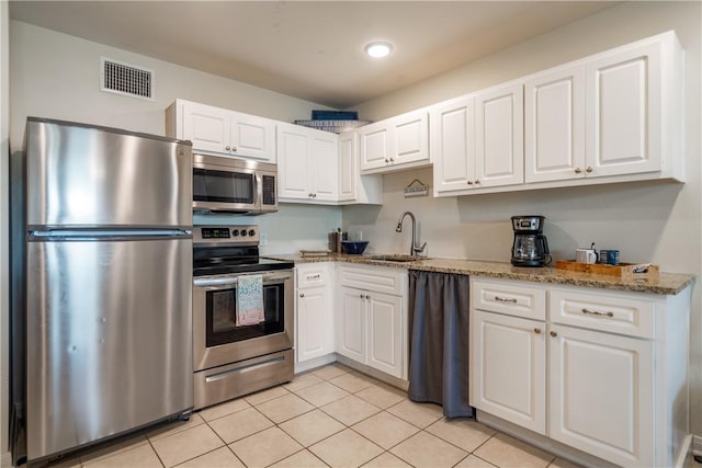kitchen with a sink, white cabinets, visible vents, light stone countertops, and appliances with stainless steel finishes