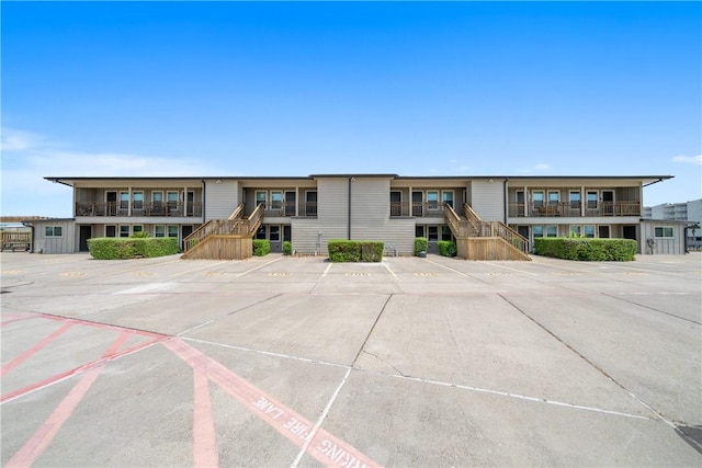view of front facade with stairway and uncovered parking
