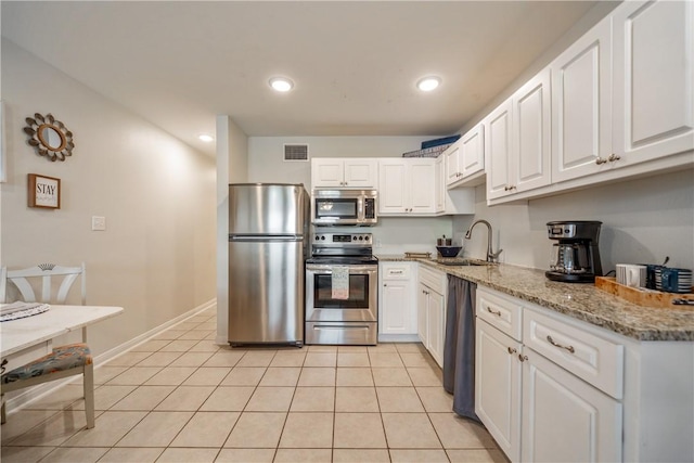 kitchen with light stone countertops, visible vents, a sink, stainless steel appliances, and white cabinets