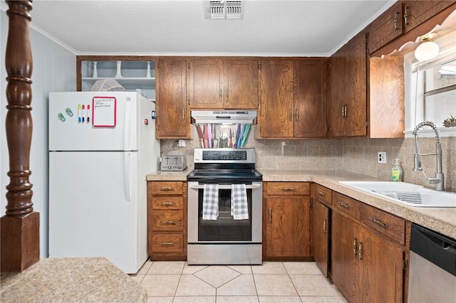 627 S Fuqua St, Rockport, TX 78382 - kitchen with appliances with stainless steel finishes, a sink, under cabinet range hood, crown molding, and light countertops