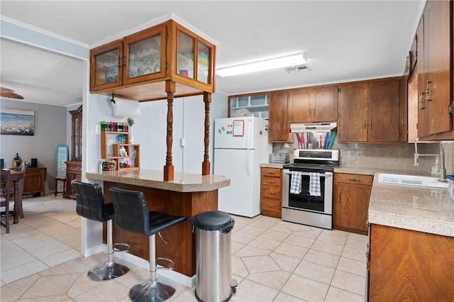 627 S Fuqua St, Rockport, TX 78382 - kitchen with electric range, freestanding refrigerator, a sink, light tile patterned floors, and under cabinet range hood