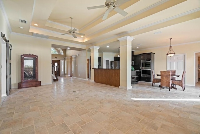 living room featuring crown molding, ceiling fan, decorative columns, a barn door, and a raised ceiling