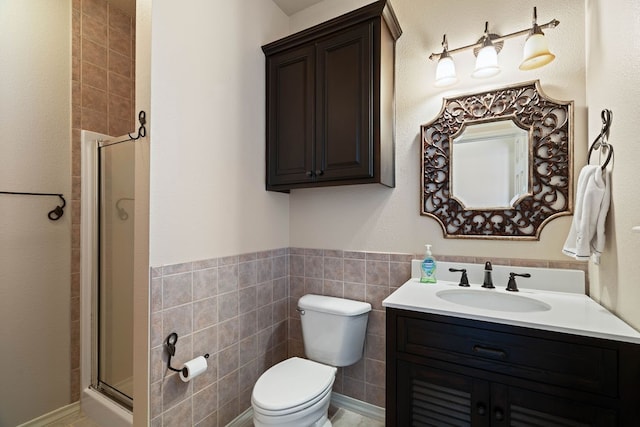 bathroom featuring vanity, toilet, a shower with door, and tile walls