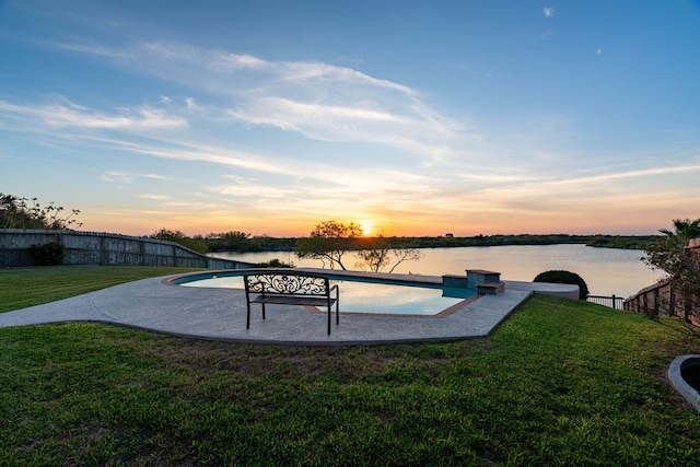 pool at dusk featuring a water view and a yard