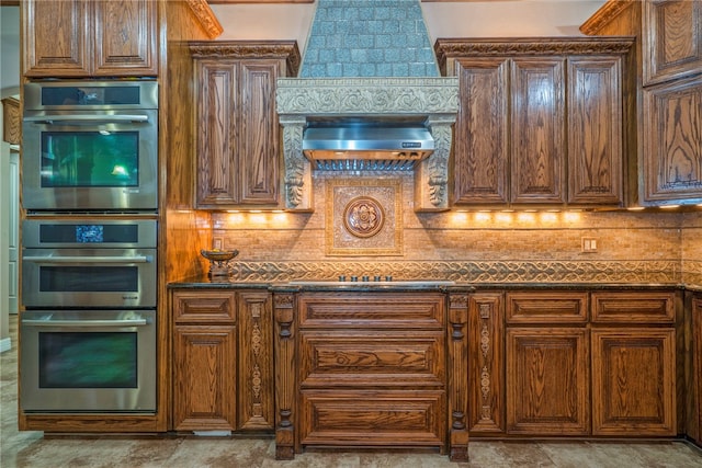 kitchen featuring decorative backsplash, wall chimney exhaust hood, dark stone counters, and stainless steel double oven