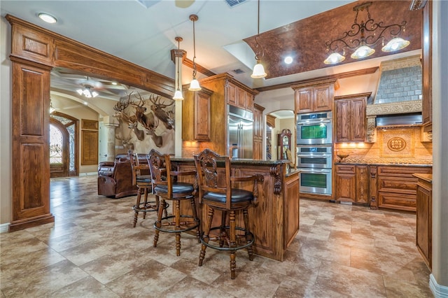 kitchen featuring crown molding, stainless steel appliances, backsplash, hanging light fixtures, and a breakfast bar area