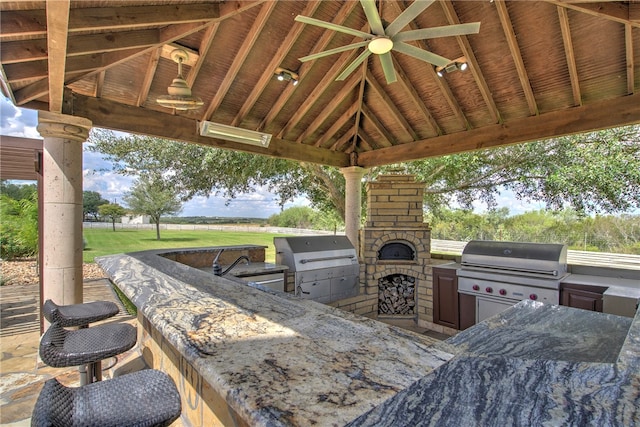 view of patio featuring ceiling fan, area for grilling, a gazebo, and exterior kitchen