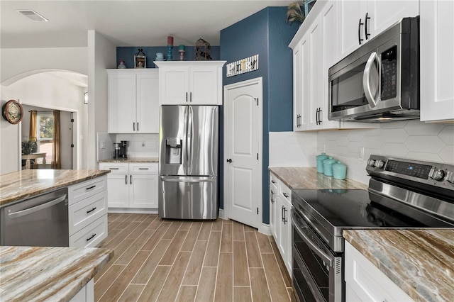 177 Glenvalley Cir, Bandera, TX 78003 - kitchen with light stone counters, visible vents, arched walkways, stainless steel appliances, and white cabinets