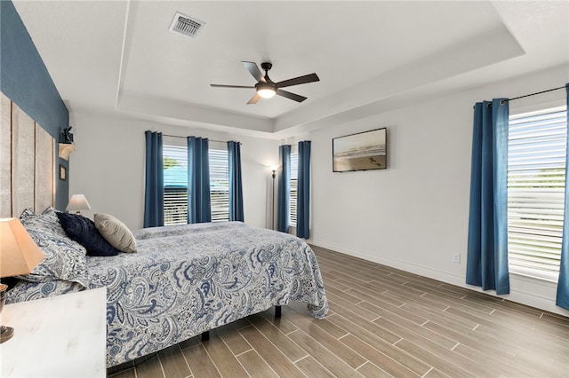 177 Glenvalley Cir, Bandera, TX 78003 - bedroom featuring wood finished floors, a tray ceiling, visible vents, baseboards, and ceiling fan