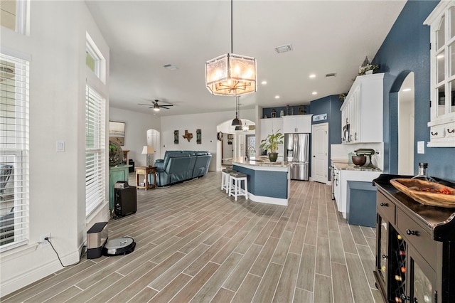 177 Glenvalley Cir, Bandera, TX 78003 - kitchen featuring a breakfast bar, visible vents, ceiling fan with notable chandelier, open floor plan, and stainless steel fridge