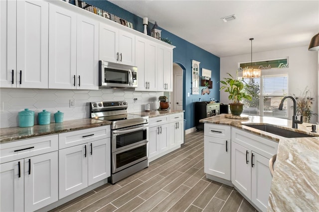 177 Glenvalley Cir, Bandera, TX 78003 - kitchen with a sink, visible vents, backsplash, a notable chandelier, and appliances with stainless steel finishes